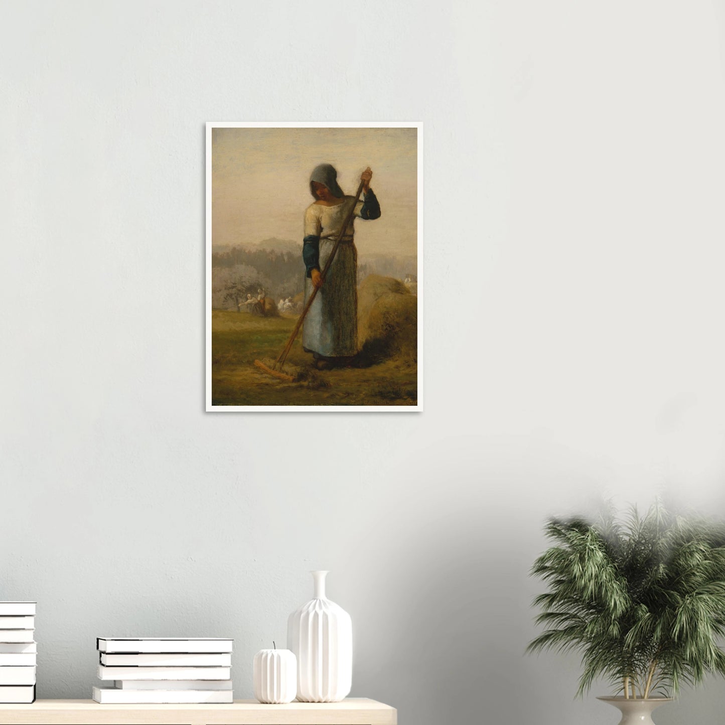 A peasant woman holds a wooden rake beside a haystack as farm workers gather hay in a distant field.