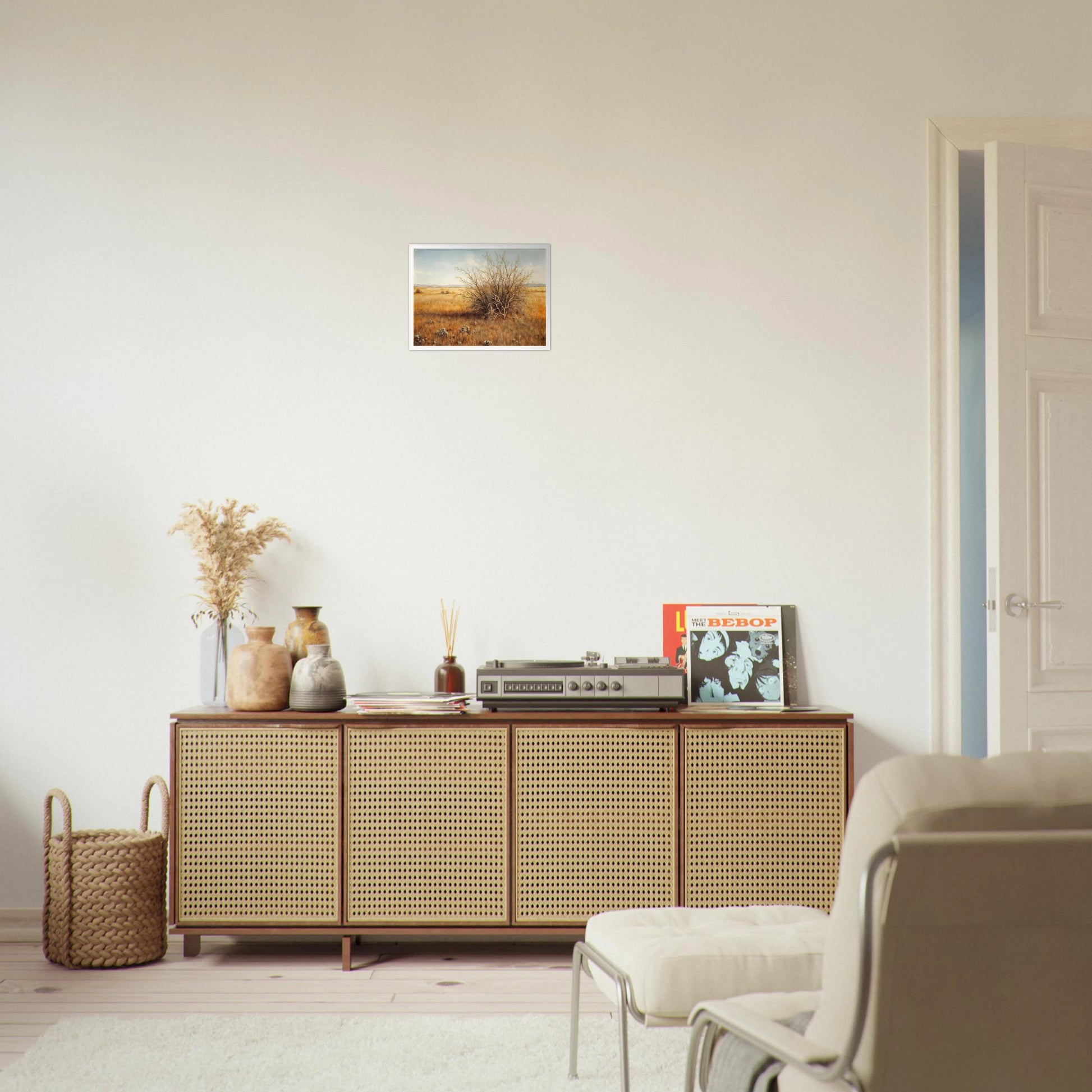 A golden-brown field stretches into the distance under a pale blue sky, with a single dry bush standing in quiet solitude.