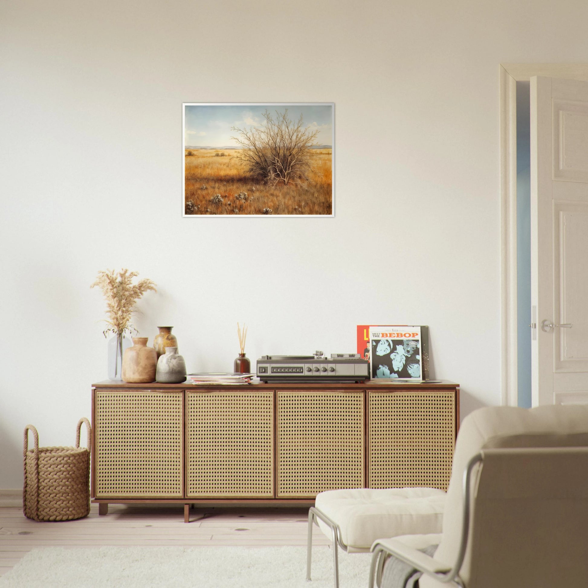A golden-brown field stretches into the distance under a pale blue sky, with a single dry bush standing in quiet solitude.