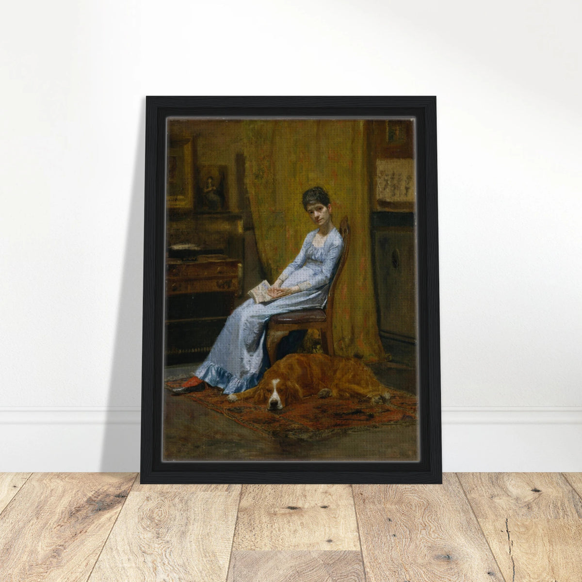 Woman in a blue dress sits with papers beside a sleeping setter dog in a dim studio interior.