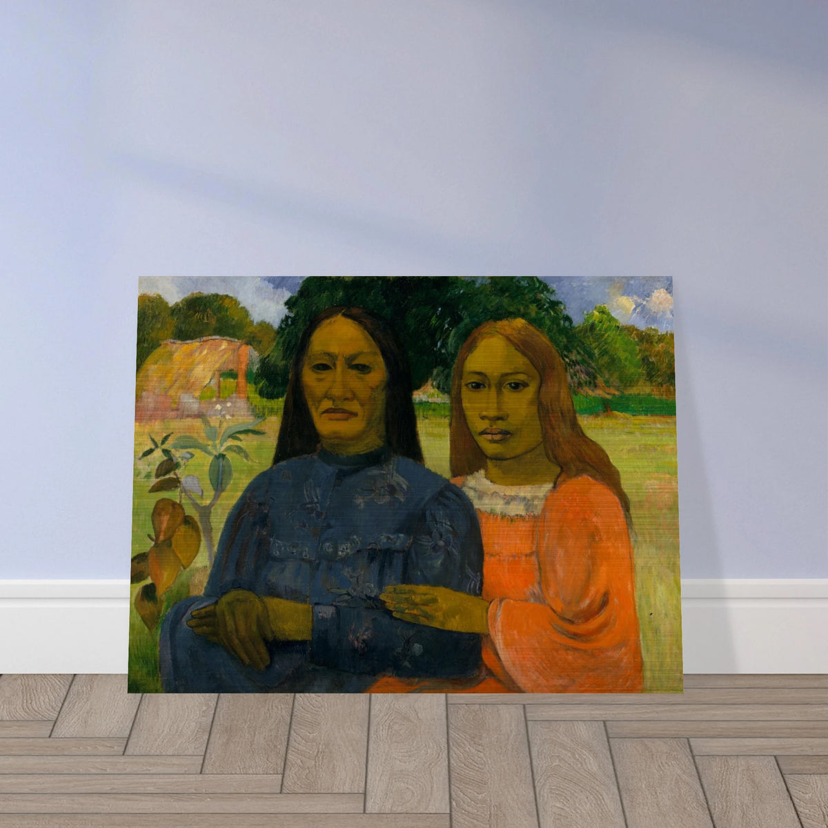 Two Tahitian women sit closely together in colorful dresses against a lush green landscape.