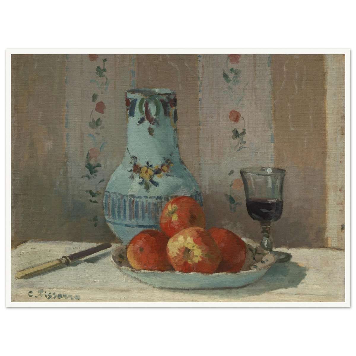 Apples on a plate with a blue pitcher, wine glass, and knife before floral wallpaper.