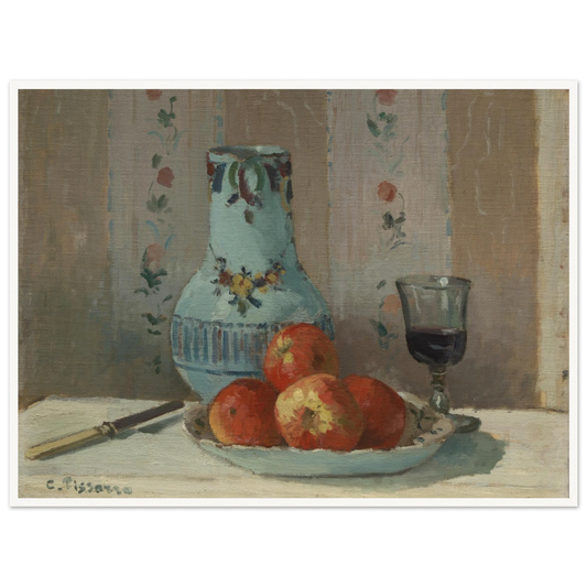 Apples on a plate with a blue pitcher, wine glass, and knife before floral wallpaper.