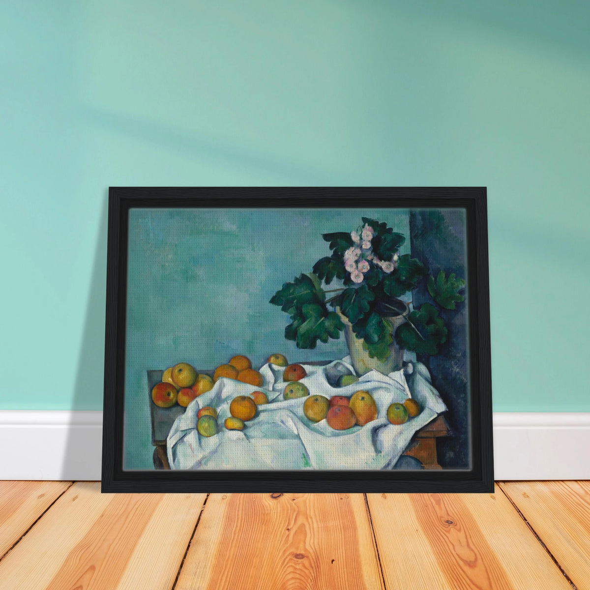 Apples on a white cloth beside a potted primrose plant against a blue-green wall.