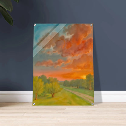Soft orange clouds drift above a winding country path, with green trees and fading sunlight across open fields.