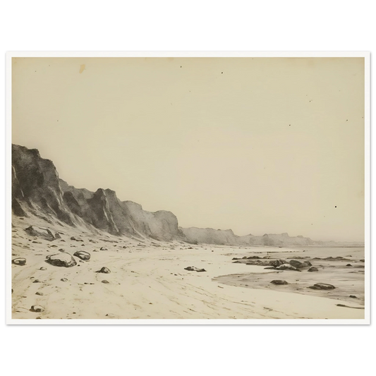 Minimal coastal landscape with pale sandy shore, rugged cliffs, scattered stones, and calm sea rendered in soft monochrome tones.