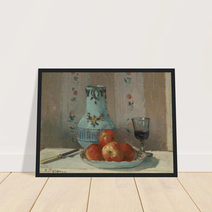 Apples on a plate with a blue pitcher, wine glass, and knife before floral wallpaper.