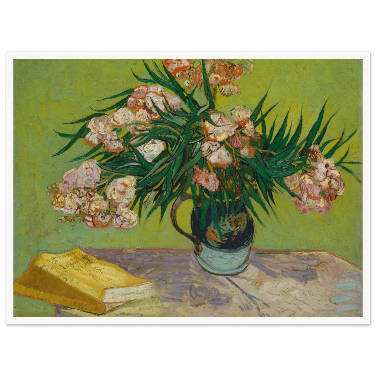 Pink oleanders bloom in a vase beside a yellow book on a green table.