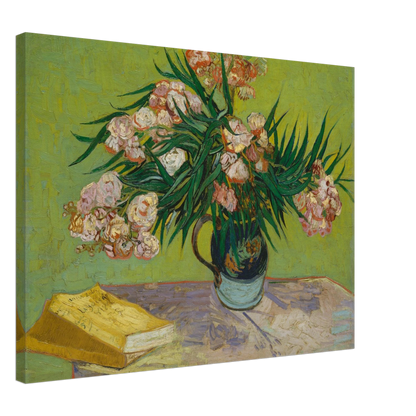 Pink oleanders bloom in a vase beside a yellow book on a green table.