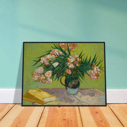 Pink oleanders bloom in a vase beside a yellow book on a green table.