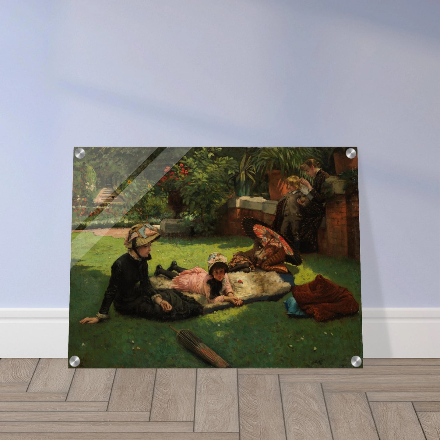 Children and women lounge in a garden with a colorful parasol under bright sunlight
