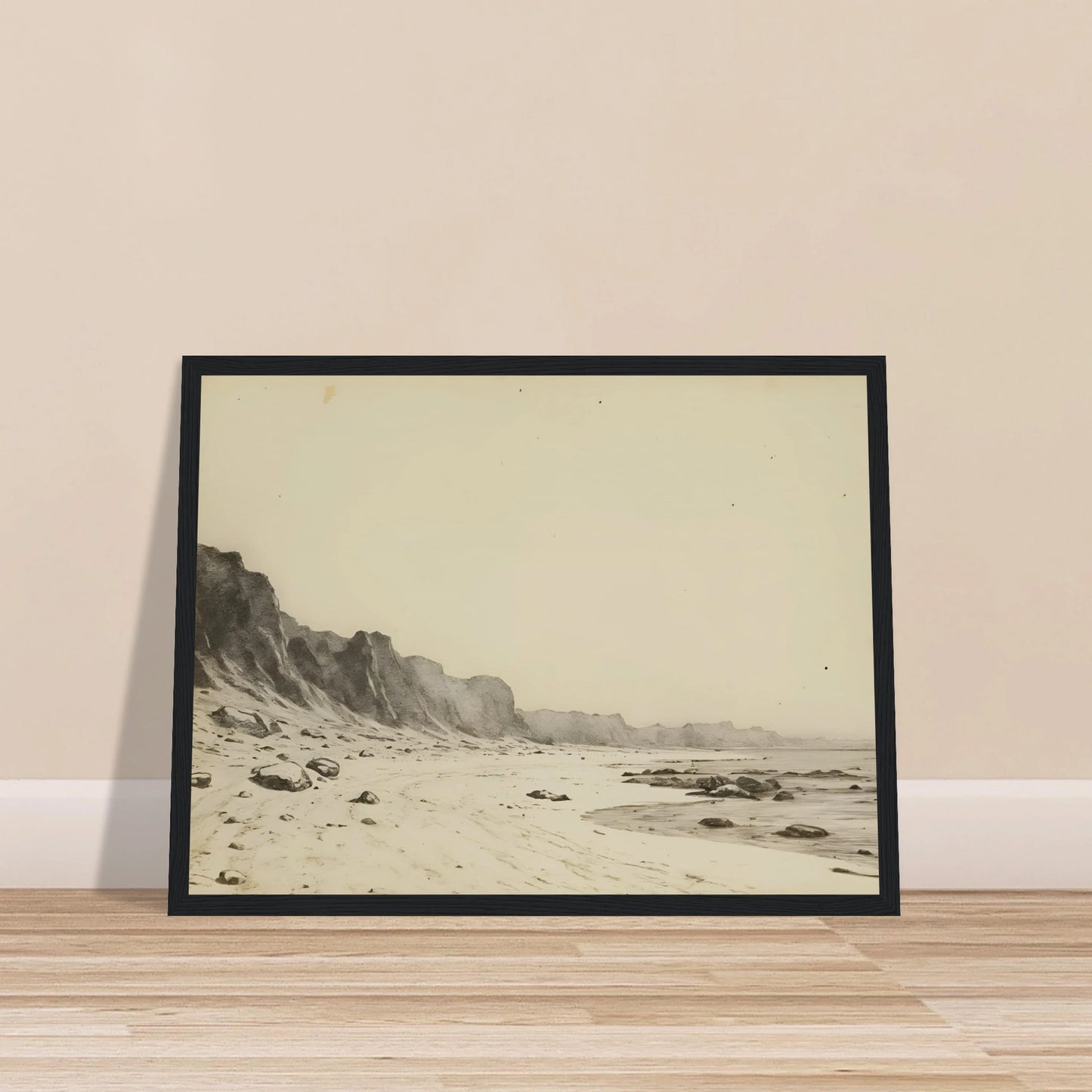 Minimal coastal landscape with pale sandy shore, rugged cliffs, scattered stones, and calm sea rendered in soft monochrome tones.