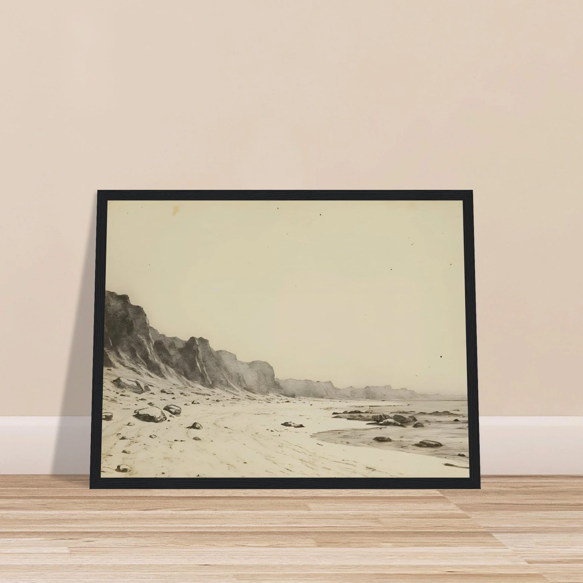 Minimal coastal landscape with pale sandy shore, rugged cliffs, scattered stones, and calm sea rendered in soft monochrome tones.